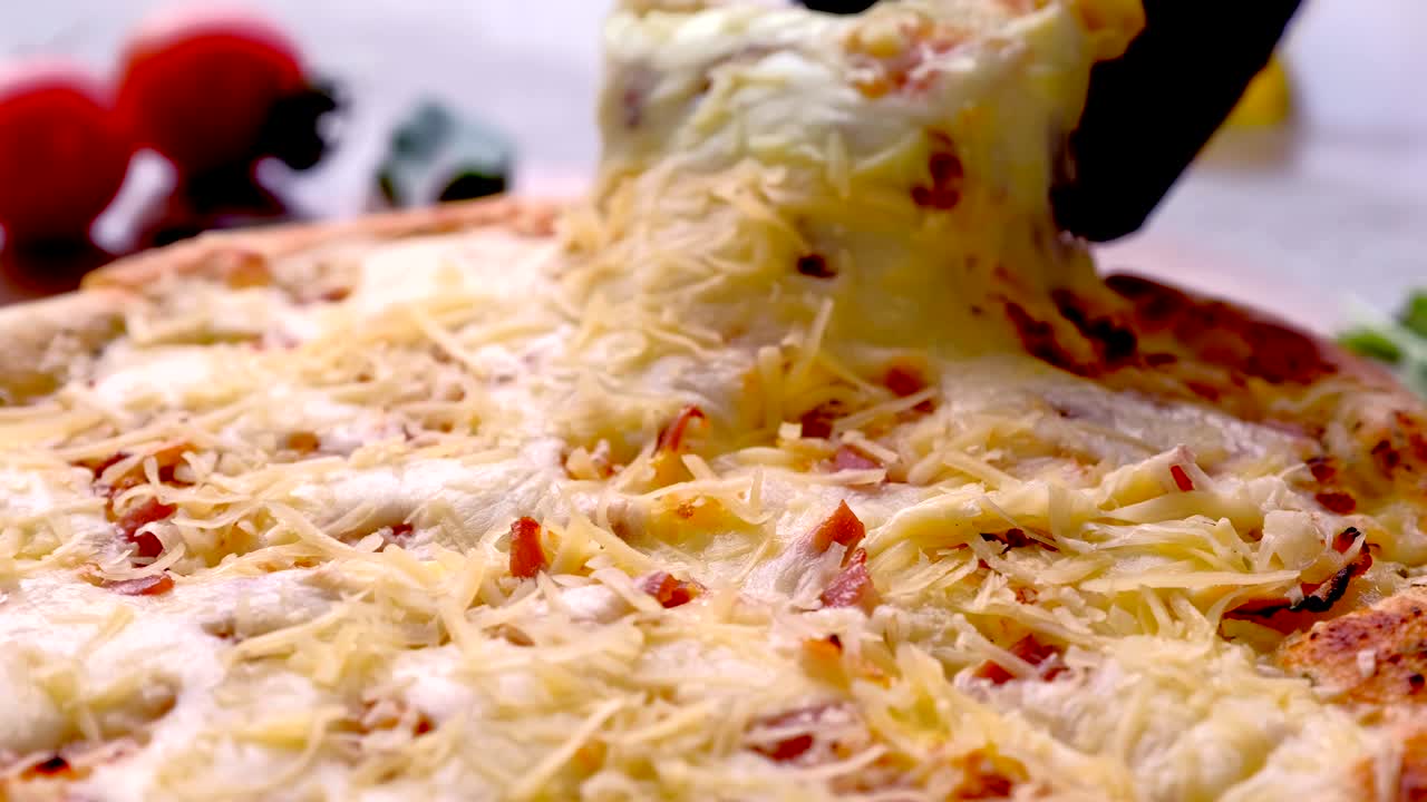 Cook takes a slice of bacon pizza with melted cheese.