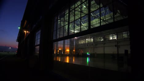 Wide-shot-of-a-large-warehouse-or-factory-at-dusk-or-sunset-as-a-large-cargo-ship-passes-in-the-distance-4