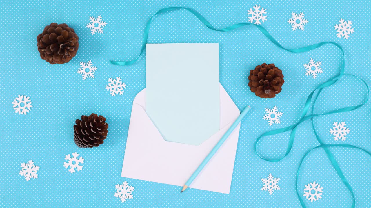 decoración de invierno con copos de nieve y conos de pino y papel en sobre con tema azul.