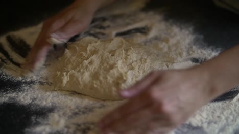 las manos de la mujer comienzan a hacer masa de pizza en harina sobre una mesa de mármol en la cocina