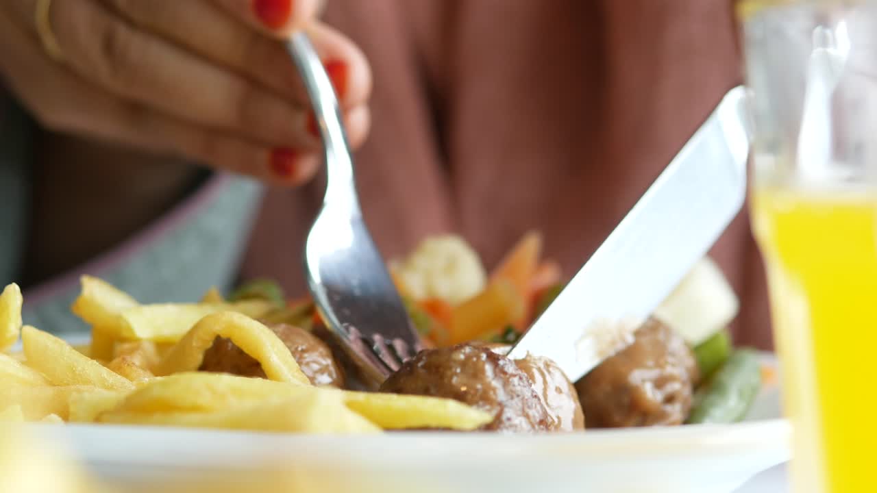 Woman eating meatballs and french fries