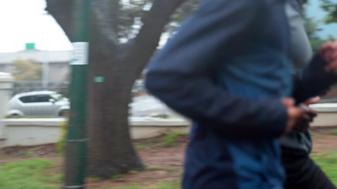 dos hombres corriendo al aire libre en un día lluvioso