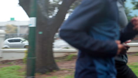dos hombres corriendo al aire libre en un día lluvioso