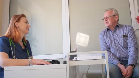 a cardiologist talks to a patient in his office. heart problems in an elderly man. modern european clinic