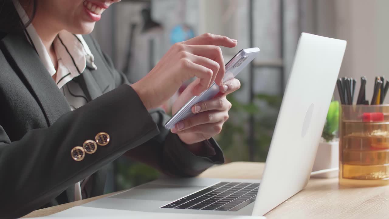 オフィスでスマートフォンとラップトップを使用する女性