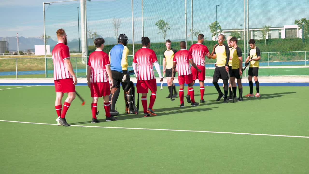 Hockey players shaking hands after match on outdoor field, showing sportsmanship