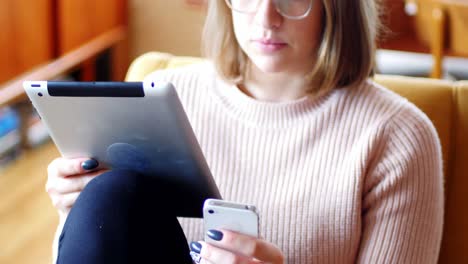mujer usando tableta digital y teléfono móvil en la sala de estar