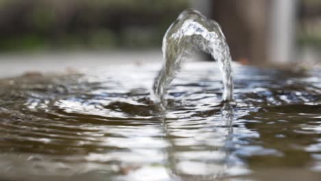 chorro de agua saliendo de una antigua fuente y haciendo olas en cámara lenta en granada, españa
