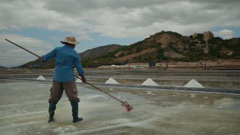 man harvesting salt in a traditional salt field