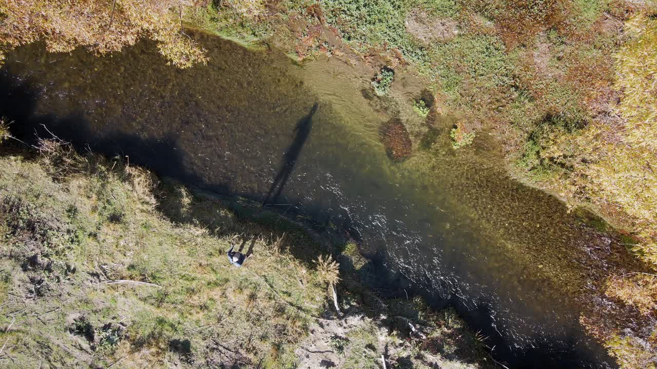 vista aérea de arriba de un pescador de mosca en la orilla del río durante la puesta de sol