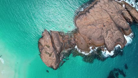 4K-Drone-Video-flying-up-showing-the-rocks-at-Twilight-Beach,-flying-upwards-to-reveal-the-crystal-clear-blue-ocean-and-white-sand-beach-in-Esperance,-Western-Australia