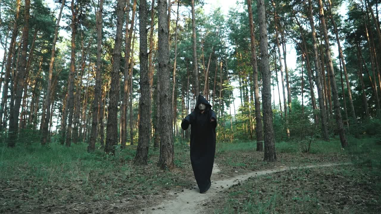 Evil ghost hooded creature walking across forest. Halloween