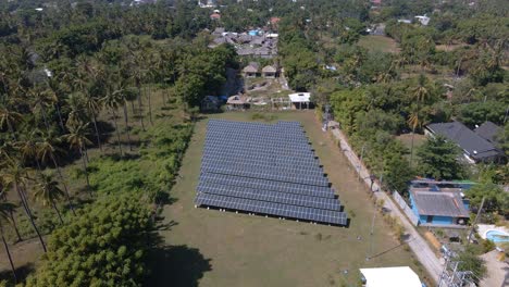 Aerial-flyover-solar-panels-area-surrounded-by-tropical-palm-trees-during-sunlight-on-Gili-Air-Island