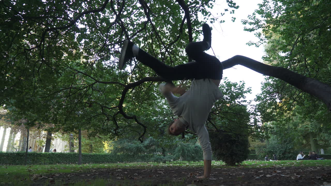 Break dancer practising tricks in the park. On sunset