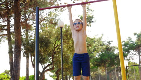 boy exercising on chin-up bar at outdoor sports ground