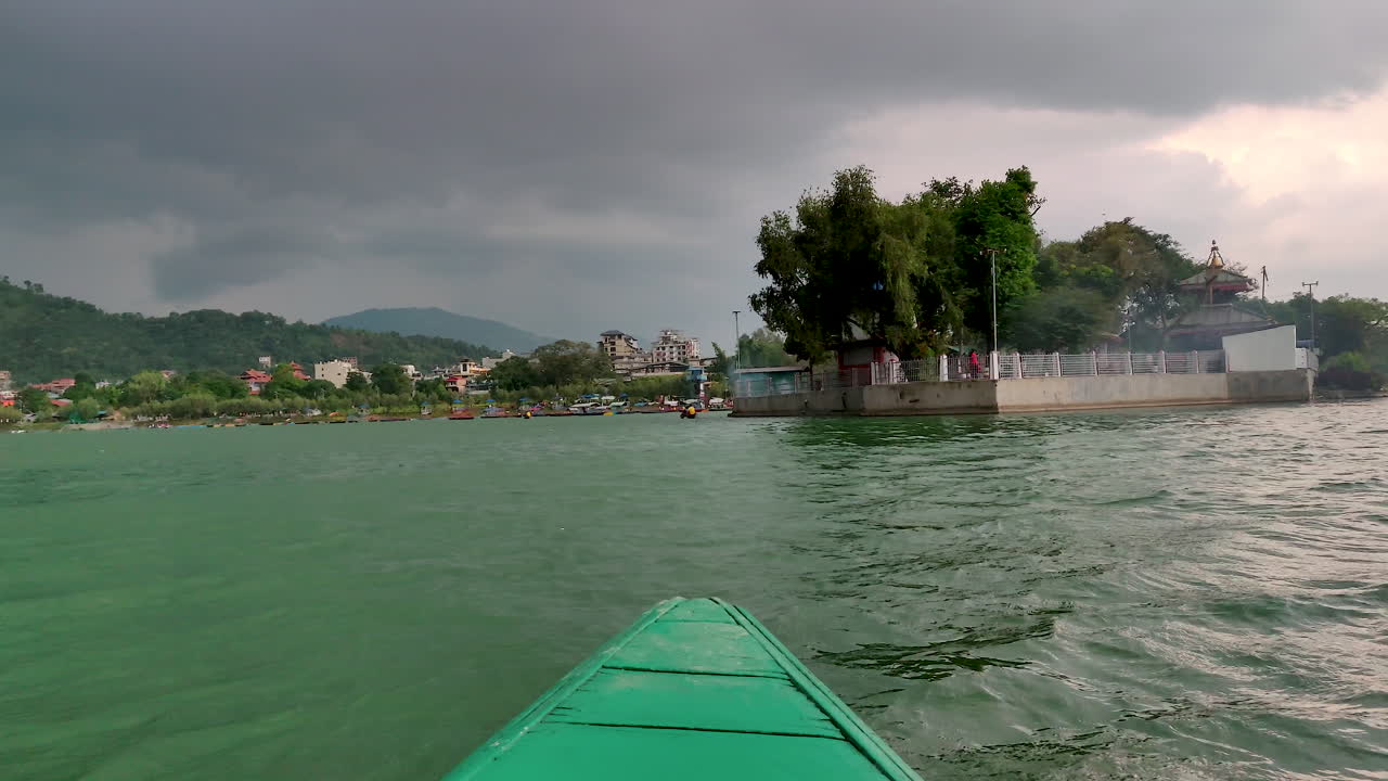 POV Sailing or Kayaking in a narrow wooden boat in a lake. Phewa Taal in Pokhara, Nepal.
