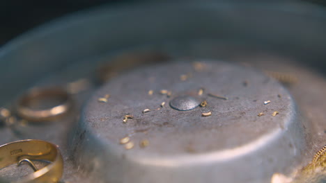 little parts of gold falls down into metal box close view