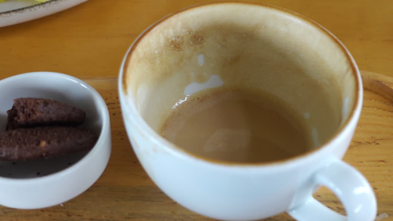 taza de café vacía en una bandeja de madera con galletas de chocolate
