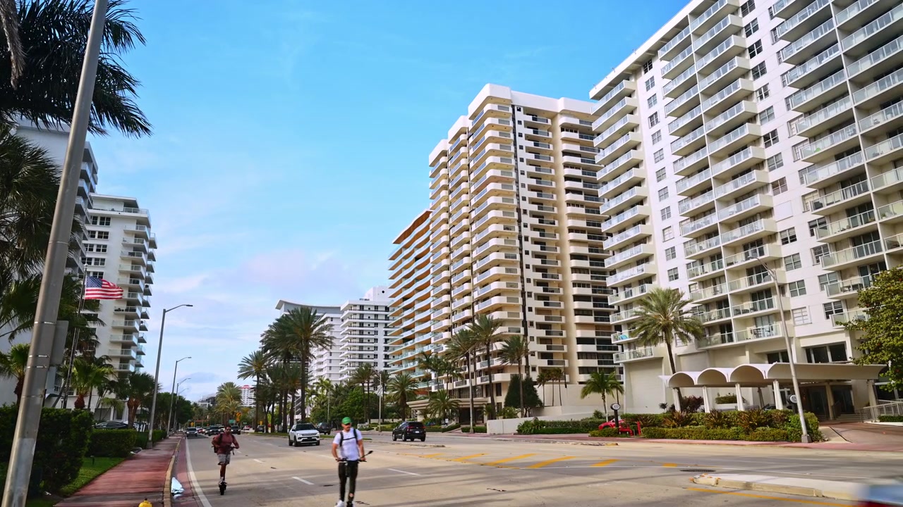 Miami, EE. UU., 16 de abril de 2026: Hilera de condominios a lo largo de un bulevar con palmeras, Miami Beach, Florida. Vista amplia de la calle con torres beige, fachadas de cristal y entrada con dosel bajo un cielo despejado