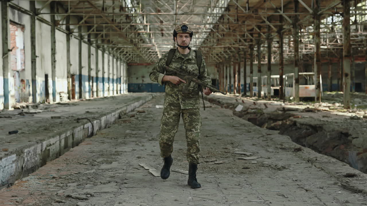 Soldier in Camouflage Uniform Patrols a Damaged Factory