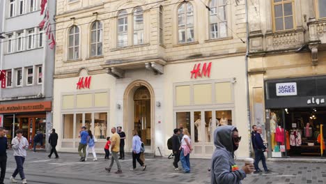 people walking in front of an h&m store in a city