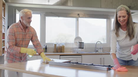 middle aged caucasian couple cleaning kitchen at home, slow motion