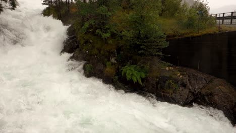 Floods-in-Norway,-water-stream-near-Langfoss-waterfall,-panning-shot