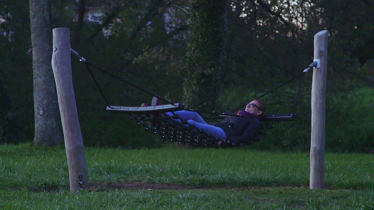 저녁에 밧줄 해먹에서 흔들리는 매력적인 모델의 긴 사진