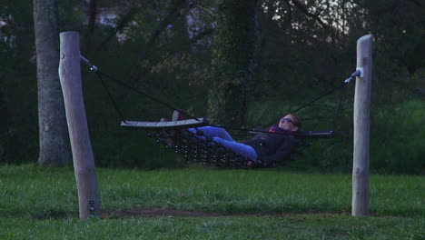 Long shot of attractive model swaying in rope hammock in the evening