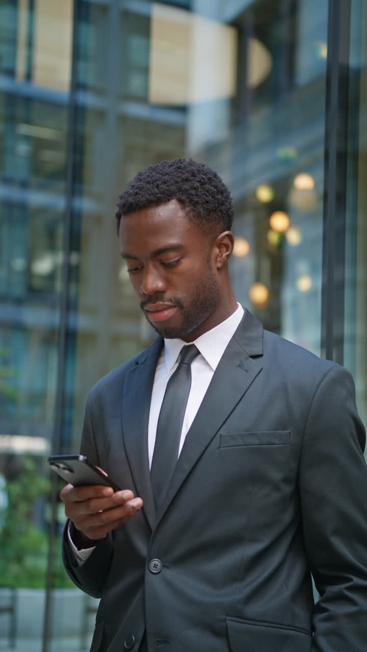 Vertical Video Shot Of Young Businessman Wearing Suit Using Mobile Phone Standing Outside Offices In The Financial District Of The City Of London UK Shot In Real Time 3