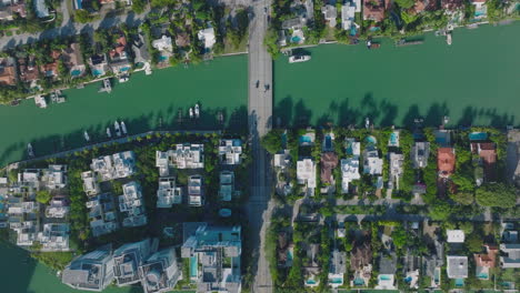 Luxurious-residences-along-water-channel-with-yachts-moored-at-bank.-Top-down-view-of-urban-neighbourhood-on-sunny-day.-Miami,-USA