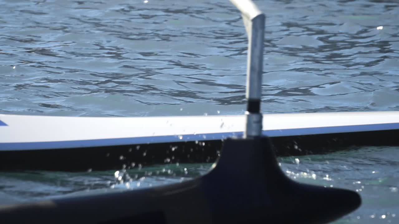 물 위의 특별 경쟁 카누에서 노를 젓는 남자의 몸을 닫습니다