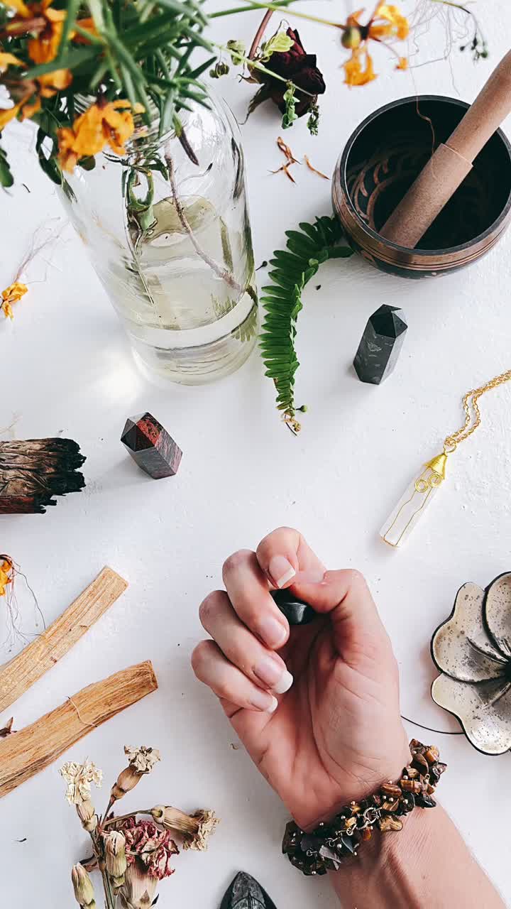Woman holding a black obsidian crystal, surrounded by crystals and spiritual items.