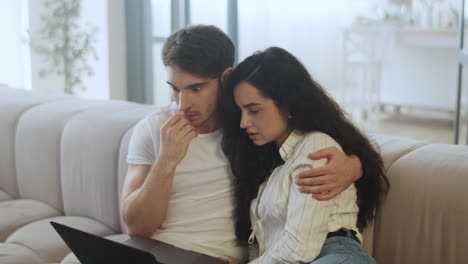 una joven pareja viendo una computadora portátil en casa en cámara lenta
