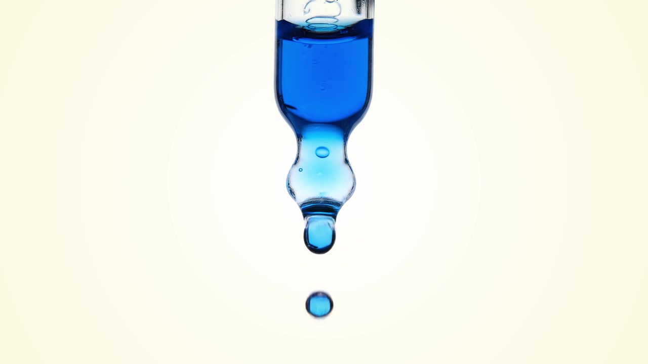 Close-up Tetesan Cairan Biru Jatuh dari Pipet Kaca
