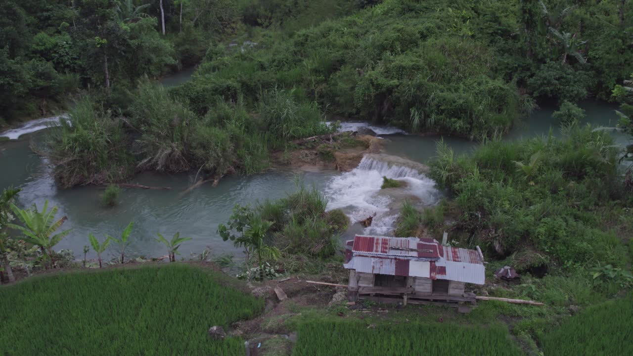 pequeña cascada con casa durante un día nublado en la isla de sumba, aérea