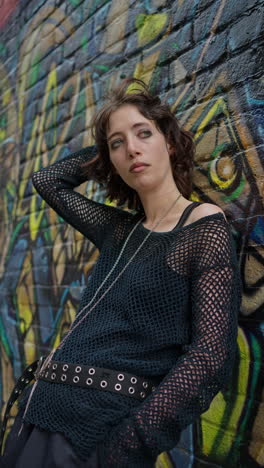 Vertical-Video-Outdoor-Fashion-Portrait-Of-Young-Alternative-Style-Woman-Leaning-Against-Graffitti-Covered-Wall-In-London-City-Street-UK-In-Real-Time-1