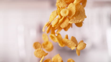 copos de maíz dorados de cereal vertidos de la caja cayendo en macro y cámara lenta