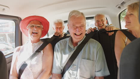 group of senior friends sitting in back of people carrier being driven to vacation