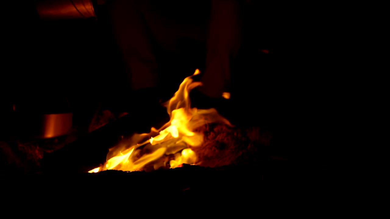 Man extinguishing campfire with water in the forest 4k