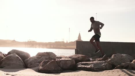 hombre corriendo sobre las rocas en la playa