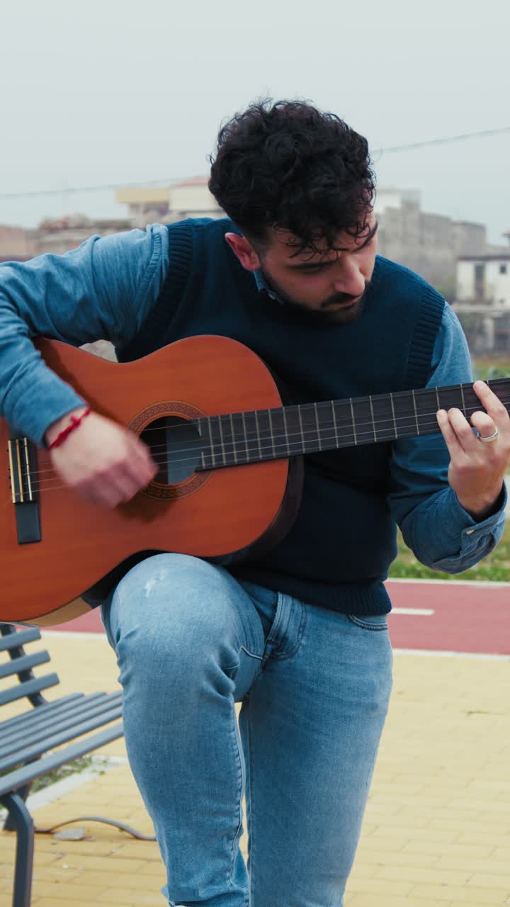 Man Surrenders to the Melody of His Guitar Playing Outdoors