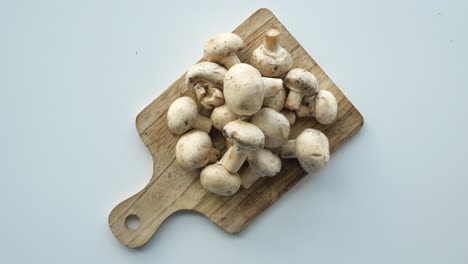 fresh button mushrooms on a wooden cutting board