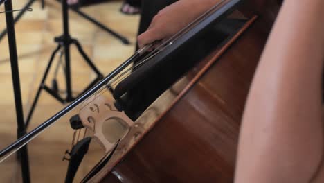 female-cellist-plays-cello-smoothly-with-bow-in-church,-slow-motion-closeup