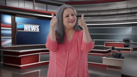 feliz periodista india senior mostrando los pulgares hacia arriba