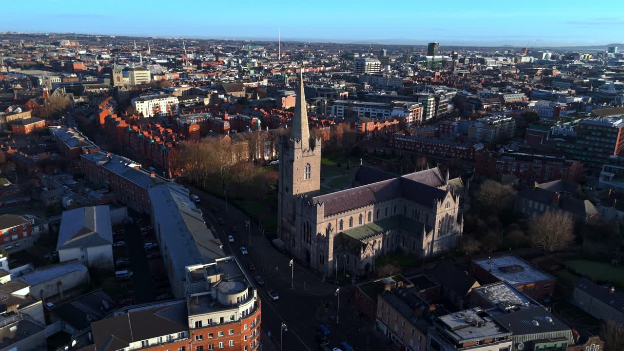 Ripresa aerea con drone della Cattedrale di San Patrizio nella capitale dell'Irlanda, Dublino. Scatto realizzato durante un'alba invernale dorata con vista sul parco, la sua erba e i suoi alberi. Architettura e città irlandese luminosa.