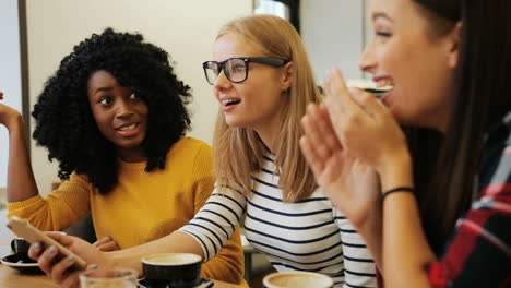 close-up view of african american and caucasian women talking and drinking coffee sitting at a table in a cafe