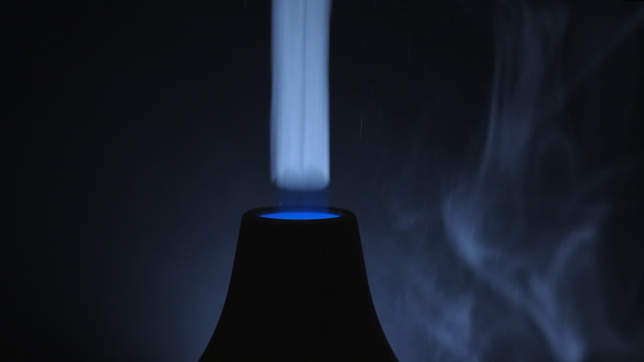 A Dark Room With A Turned On Ultrasonic Diffuser Releasing White Smoky Aromatic Air From Essential Oil - Close Up Shot