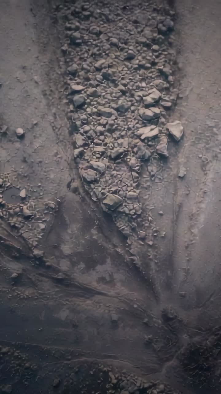 Video verticale: drone in drifting che segue un piccolo spostamento verso il basso, rivelando un cumulo triangolare e delle scanalature