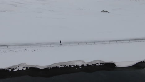 woman walking on winter road, snowy icelandic countryside